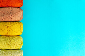 Yellow-orange background of skeins of cotton yarn arranged in a row on the right. Materials for knitting. Textile industry. 