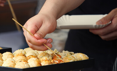 Lower body of chef making Takoyaki, traditional Japanese balls at street market stand at Embassies Festival in Prague. Closeup, partial motion blur.