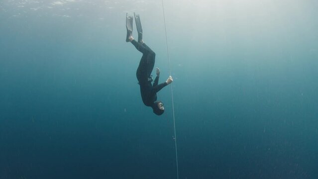 Male freediver descending along the rope during free diving work out in the open sea