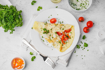 Tasty omelet with tomatoes and parsley on light table