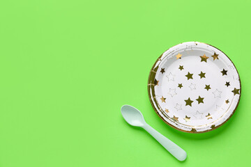 Paper disposable plate and spoon on green background