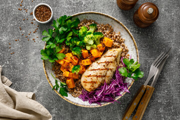 Grilled chicken breast with buckwheat, roasted butternut squash, broccoli, fresh greens and red cabbage. Healthy food, lunch menu, top view