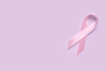 Pink awareness ribbon on lilac background. Breast cancer concept