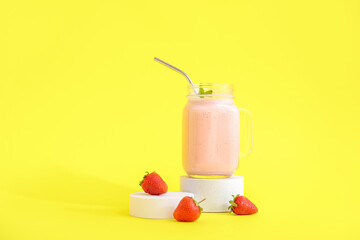 Mason jar of tasty strawberry smoothie on yellow background