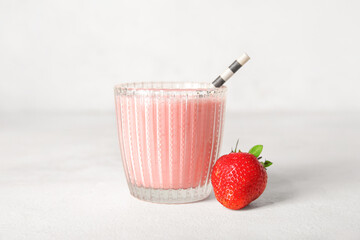 Glass of tasty strawberry smoothie on light background