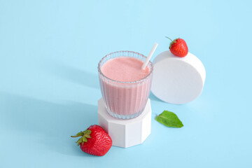 Glass of tasty strawberry smoothie on blue background