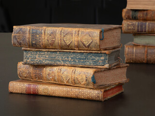 Pile of old vintage books lying on a black table.