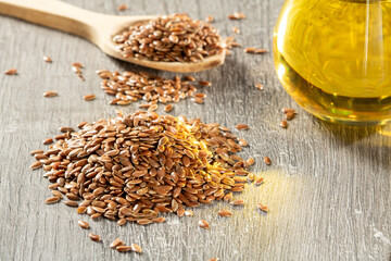 A bunch of flax seeds and a jar of linseed oil on a wooden table