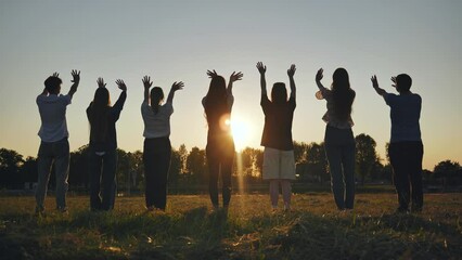 Seven friends waving at the sunset.