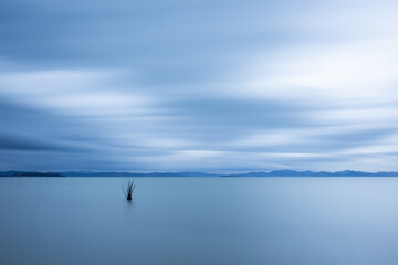 Minimalist view of fishing net poles on a lake, with perfectly still water and empty sky at dusk - 640372000