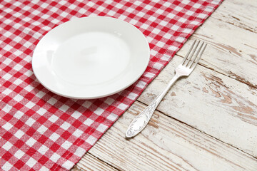 Clean plate, fork and napkin on light wooden background
