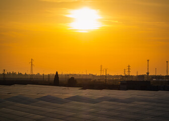 Sunset over the industrial zone. Electric poles and photovoltaic panels during sunset