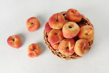 Wicker bowl with sweet fig peaches on white background