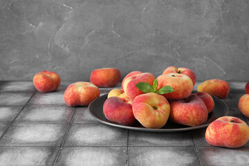 Fototapeta na wymiar Plate with sweet fig peaches and mint on grey tile table