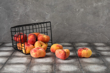 Basket with sweet fig peaches on grey tile table