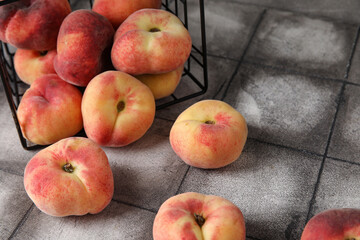 Basket with sweet fig peaches on grey tile table