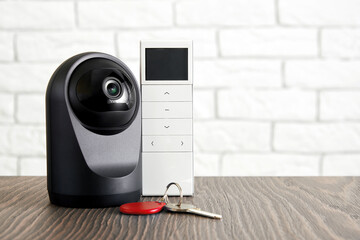 Concept of home safety and security equipment. IP Web camera with remote controller and house keys...