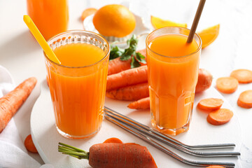 Glasses of fresh carrot juice with orange on white background