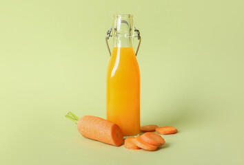 Bottle of fresh carrot juice on green background