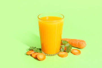 Glass of fresh carrot juice with parsley on green background