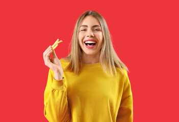 Beautiful happy young woman with french fries on red background