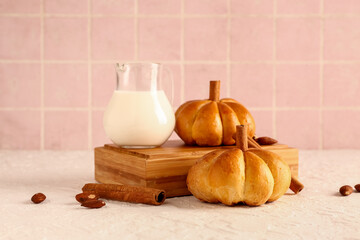Wooden box with tasty pumpkin shaped buns and jug of milk on table