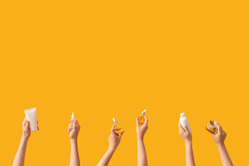 Women with cosmetic products on yellow background