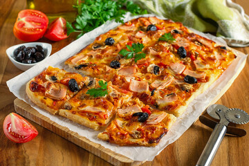 Fresh homemade rectangular pizza with ham, tomatoes and olives - 640391087