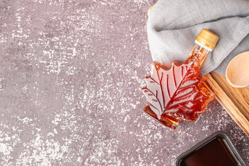 Bottle of tasty maple syrup on grey background
