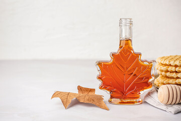 Bottle of tasty maple syrup on light background
