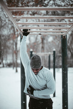 Young fit and athletic african man feeling a sharp pain in his chest after working out and exercising in a park during winter and snow