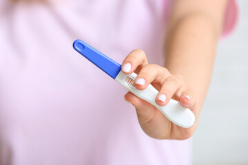 Obraz na płótnie Canvas Female hand with positive pregnancy test, closeup