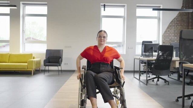 A modern young businesswoman in a wheelchair is surrounded by an inclusive workspace