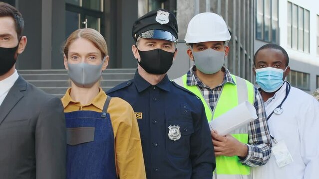 Motion camera view of diverse people of different occupations standing outdoors in protective masks. Diversity of professions. Pandemic concept. COVID-19. Multicultural team of workers.