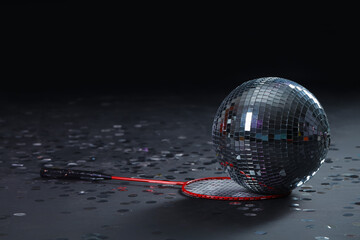 Disco ball with tennis racket and confetti on dark background