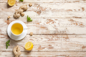 Cup of ginger tea with lemon and mint on white wooden background