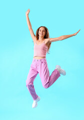 Fototapeta na wymiar Young woman jumping on blue background