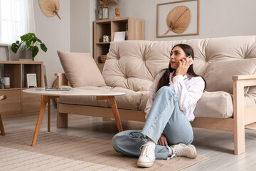 Young woman talking by mobile phone in living room