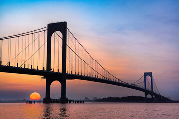 View of the Whitestone Bridge in Queens, New York City at sunset with the water of the Long Island Sound in view.