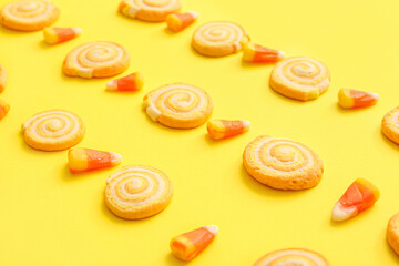 Tasty cookies with candy corns for Halloween celebration on yellow background