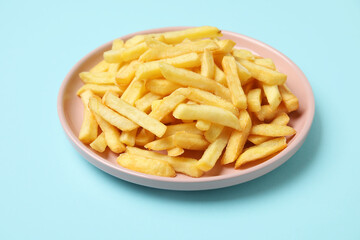 Plate with golden french fries on blue background