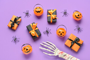 Composition with gift boxes, pumpkins, skeleton hand and spiders on purple background. Halloween celebration concept