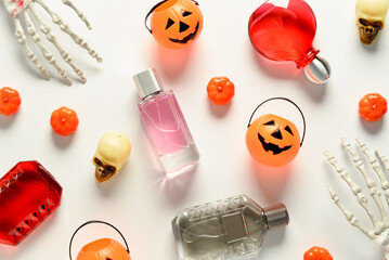 Bottles of elegant perfume with skeleton hands, skulls and pumpkins for Halloween celebration on...