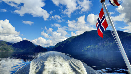 Fjord Cruise Bergen - Mostraumen, Norway. View of the fjord from the boat with Norwegian flag from the right side. Travel, Scandinavia