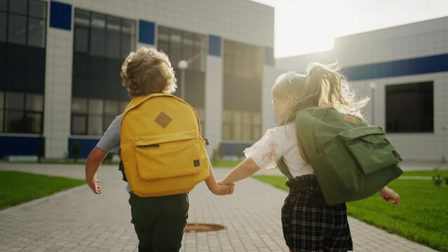 Children Running To School In Sunny Morning, Back View Of Little Boy And Girl With Backpacks