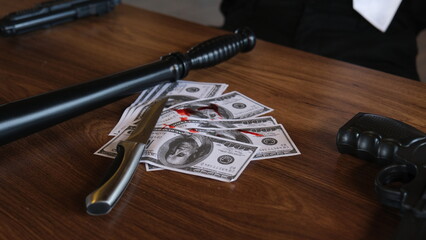 bloody knife, gun and money on the table. knife, gun, blood and american dollars. 