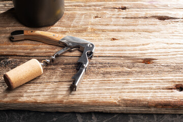 Corkscrew and wine cork with a bottle on a vintage table. Close-up. Place for text.