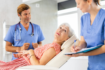 Obraz premium Professional physician consulting woman patient in clinic. Nurse filling form at consultation.