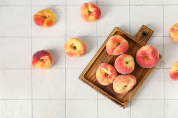 Wooden board with sweet fig peaches on white tile background