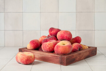 Wooden box with sweet fig peaches on white tile background